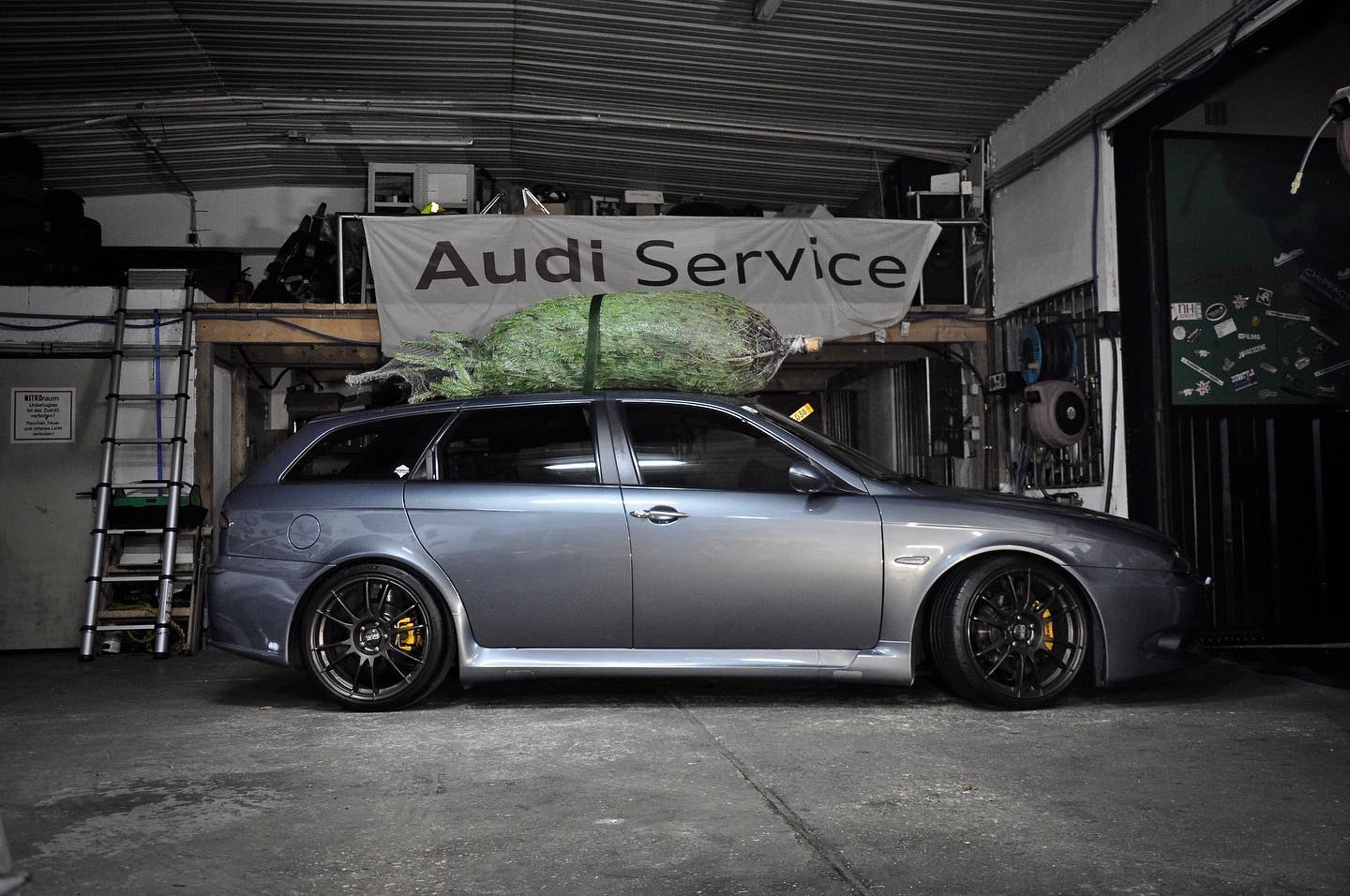 Blaugrauer Alfa Romeo 156 GTA Sportwagon mit dunklen Felgen in einer Werkstatt