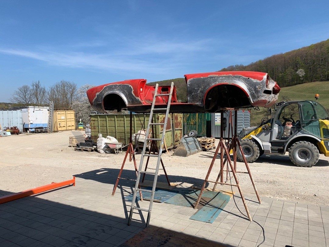 Rote Karosserie eines alten Fiat auf Böcken im Freien